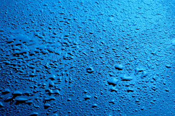 Many water droplets on a dark blue background as a texture, background or pattern