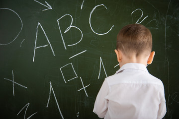 A small child is standing at the school board.