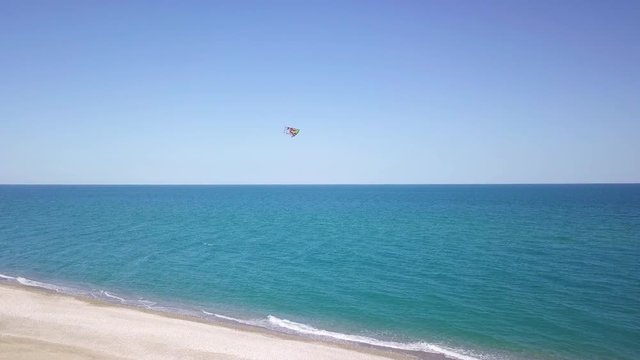 Aquilone colorato che vola in spiaggia con sfondo del mare blu.