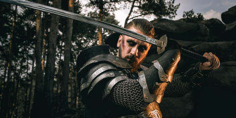 mystery scarface knight in armor with sword and crossbow in the forest