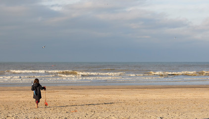 Fototapeta na wymiar Little girl walking towards the sea on an empty beach in winter