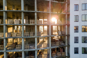 Modern building under construction detail, concrete frame, window openings and scaffolding background.