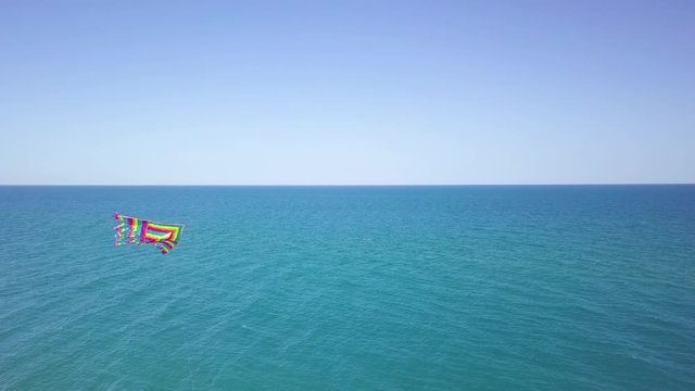 Aquilone colorato che vola in spiaggia con sfondo del mare blu.