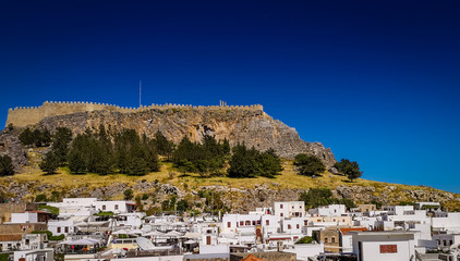 Lindos ,Rhodes/Greece May 2 2019 :the white houses in the historic village and the acropolis in the...