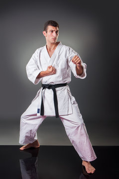 Handsome young male karate player posing on the gray background