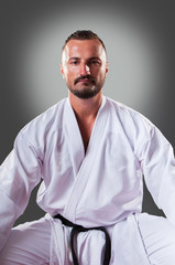 Portrait of handsome male karate player posing on the gray background