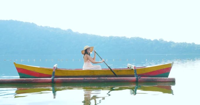Beautiful girl kayaking on the catamaran at the ulun datu pura bratan temple, in Bali.