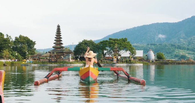 Beautiful girl kayaking on the catamaran at the ulun datu pura bratan temple, in Bali.