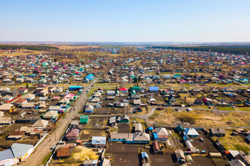 Aerial view of a large number of small houses with colored roofs on the outskirts of a small provincial town of Lenin Kuznetsk on an spring sunny day with the road and cars