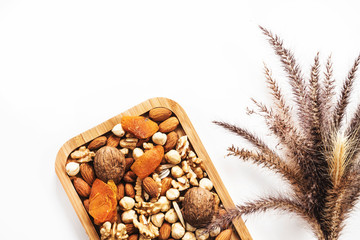 Wooden bowl with mixed nuts on white table top view. Healthy food and snack. Walnut, pistachios, almonds, hazelnuts