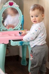 a small child plays in front of a toy mirror in the nursery