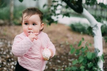little girl in the garden on the background of greenery and trees very cute eating ice cream finger in a waffle Cup