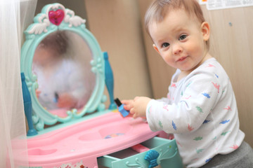 a small child plays in front of a toy mirror in the nursery