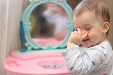 a small child plays in front of a toy mirror in the nursery