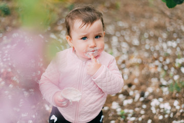 little girl in the garden on the background of greenery and trees very cute eating ice cream finger in a waffle Cup