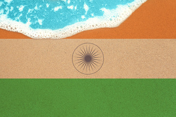 Sea wave on the sunny sandy beach with flag India. View from top on surf.