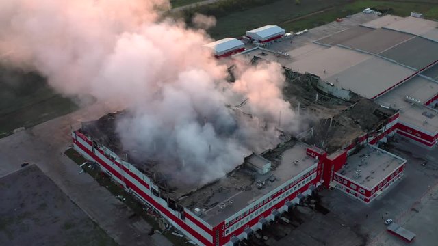 Aerial view of smoke from burning industrial building, fire in warehouse building