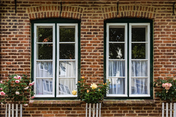 Mit Rosen dekorierte Fenster an einer Backsteinfassade