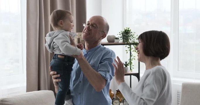 Grandparents dancing with infant granddaughter at home