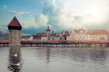 Tower and bridge across river in Lucerne, Switzerland during twilight hour.