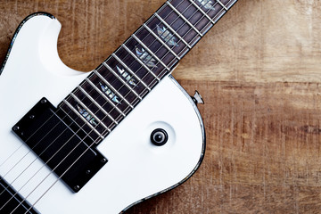 Body and fretboard of modern electric guitar on rustic wooden background. Top view. Copy space. 