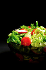 Salad in a black glass bowl on a black background