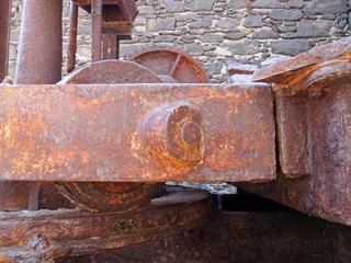 close up of old rusty crane mechanism in the old coal docks in funchal Madeira against a stone wall