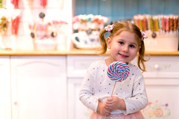 Smiling little girl eating candy lollypop.