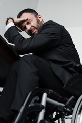 low angle view of depressed businessman crying while sitting in wheelchair