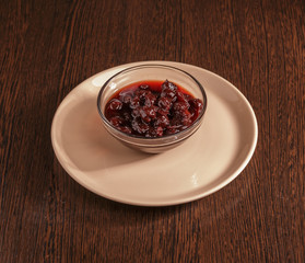 Cherry jam in a glass container on the table.