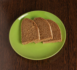 Pieces of rye bread lie on a plate on the table.