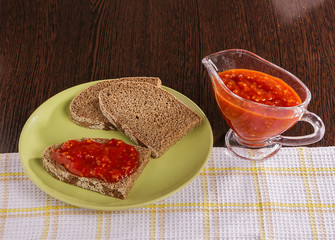 Pieces of rye bread and thick tomato sauce on a plate on the table.