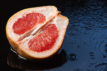 cut pink grapefruit lies in water, on water circles from drops, juicy citrus fruits