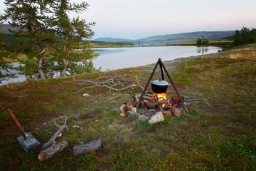 Tourist pot on the fire on the river bank