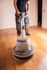 Handwerker ölt Parkettboden mit großer Poliermaschine