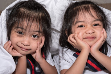 happy little girls twins sister in bed under the blanket having fun, smiling and wacky