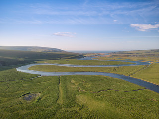 Stunning aerial drone landscape image of meandering river through marshland at sunrise