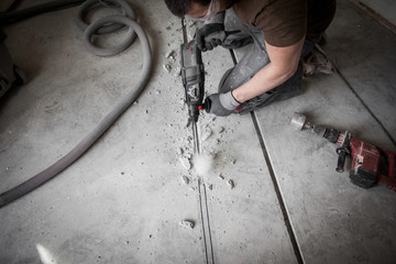 Bauarbeiter stemmt Schlitze in den Betonboden auf der Baustelle