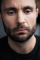 portrait of frustrated, depressed handsome bearded man looking down