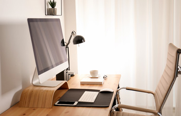 Stylish workplace interior with modern computer on table. Mockup for design