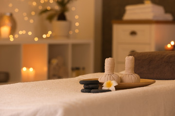 Herbal compresses and stones on massage table in spa salon. Space for text