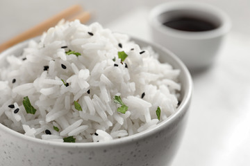 Bowl of tasty cooked rice served on table, closeup