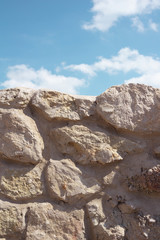 Wall made of stone and rock / Blue sky with white clouds. Warm filter and muted black