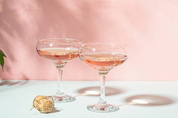 Champagne or wine in elegant glasses on a pink background bright light. Copy space. Selective focus.
