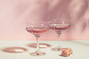 Champagne or wine in elegant glasses on a pink background bright light. Copy space. Selective focus.