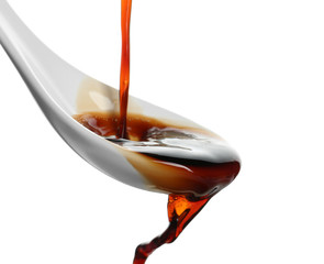 Pouring soy sauce into spoon against white background