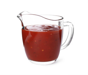 Glass jug with red sauce on white background