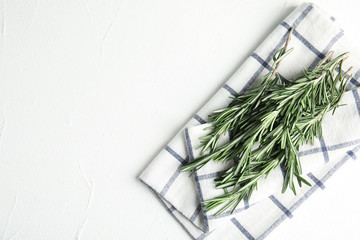 Fresh green rosemary and napkin on white table, top view. Space for text