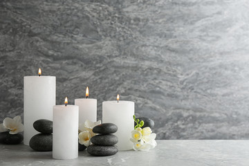 Composition of burning candles, spa stones and flowers on table. Space for text