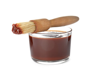 Glass dish of barbecue sauce with basting brush on white background